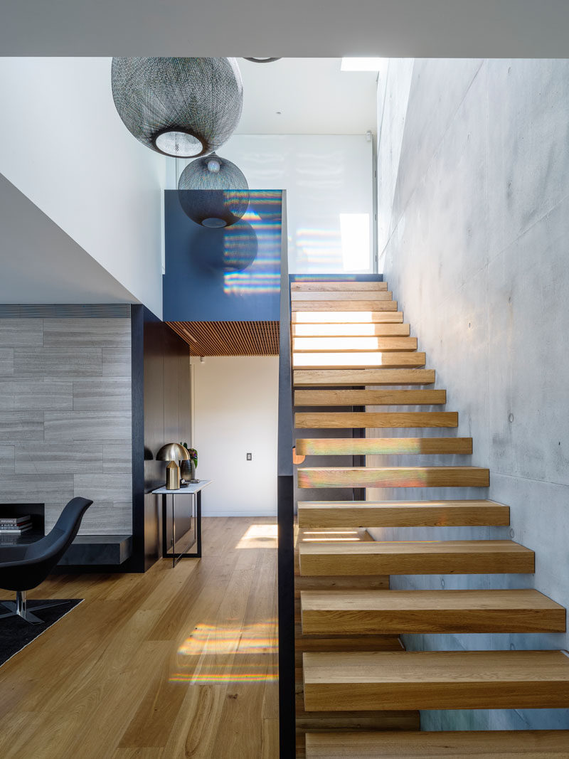 Timber clad cantilevered stairs, positioned against the off-form concrete wall, guide you to the upper level of this home.