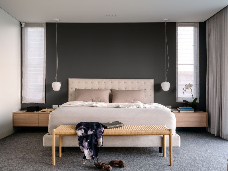 A dark feature wall contrasts the soft color palette of the bed and furniture.