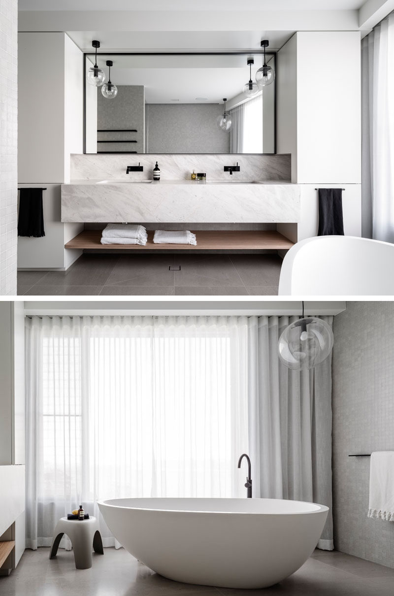 In this master bathroom, the vanity has dual sinks, a large black framed mirror and a standalone soaker bathtub.