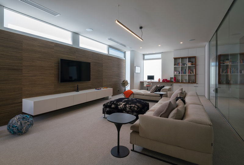 This living space with a wooden feature wall behind the tv, has a built-in desk and cabinetry at one end of the room.