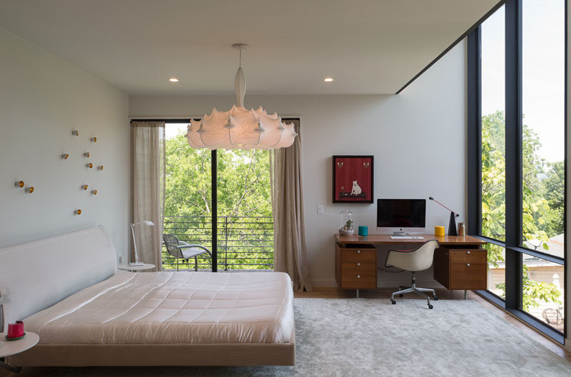 In this bedroom, large windows flood the room with light, and sliding glass doors provide access to the small balcony.