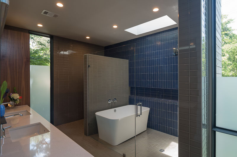 In this bathroom, the shower and bath are separated from the rest of the space with a glass wall/door, and the toilet is tucked behind the tiled wall.