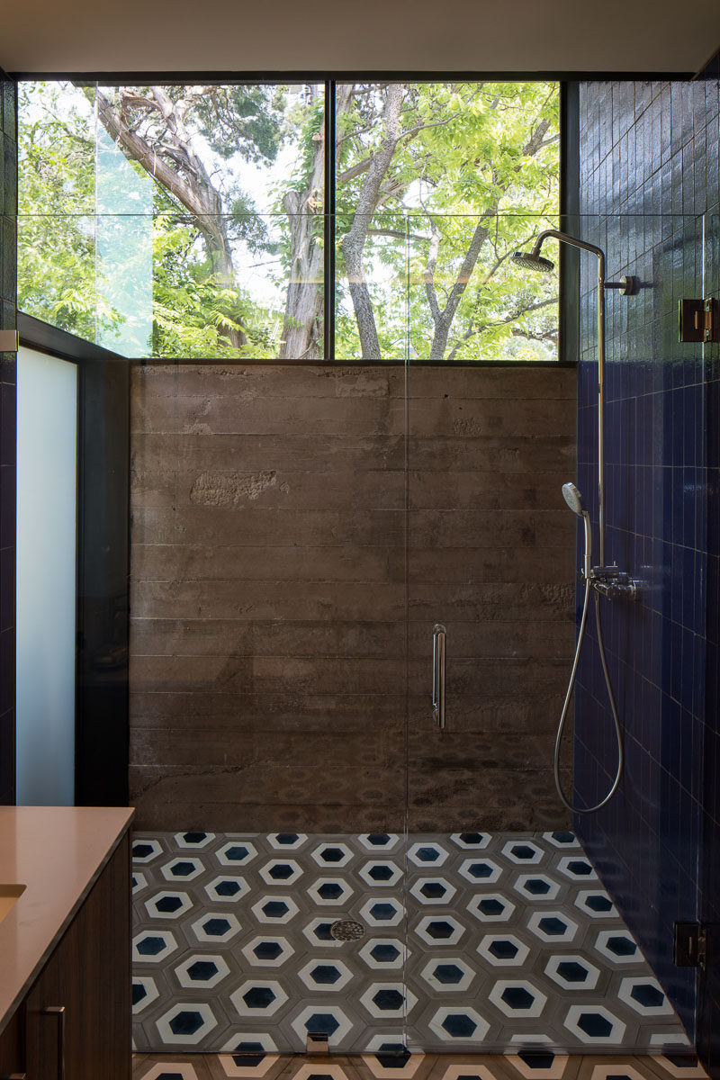 Poured-in-place concrete walls, geometric tiles and large windows make up the design of this bathroom.