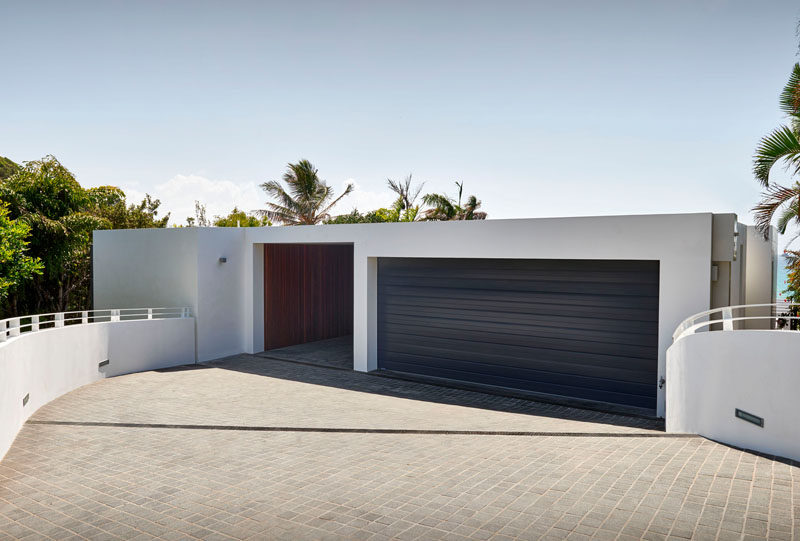 A dark garage door contrasts the white siding of this home.