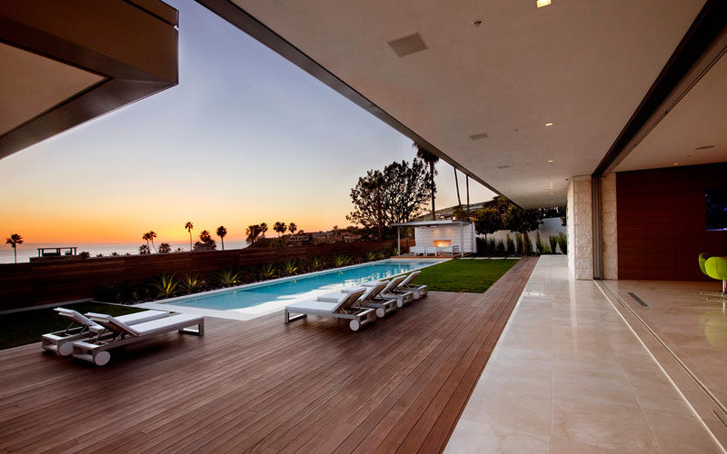 The backyard with swimming pool has a couple of small grassy areas, lots of room for relaxing in the sun and an outdoor lounge area with fireplace.