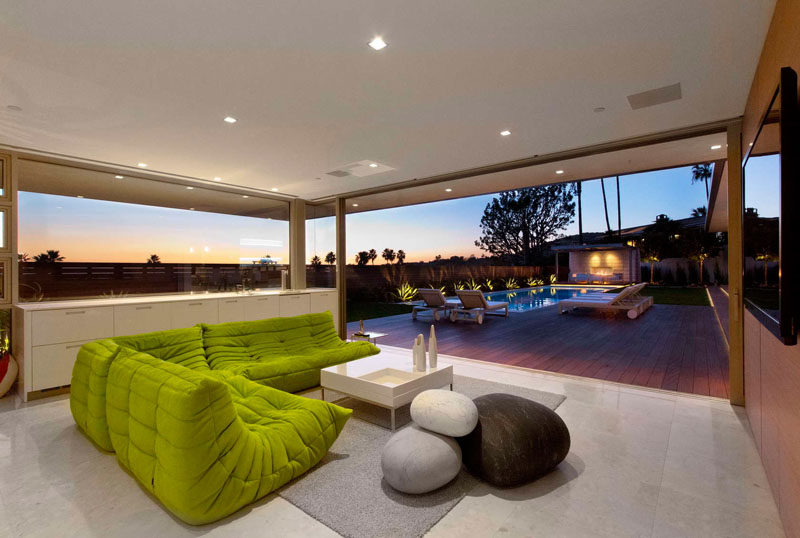 This comfortable living room has a splash of color with the lime green sofa, and it opens up for a view of the swimming pool.