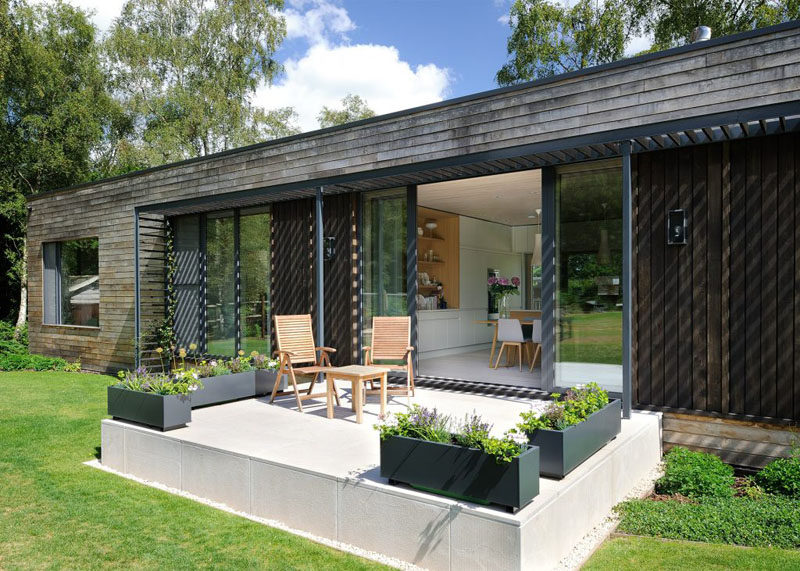 This contemporary mobile home has a small patio area with chairs and planters.