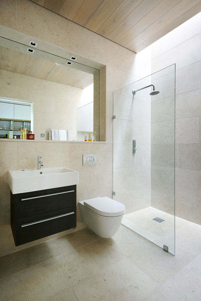 In this bathroom, the mirror is set back, providing space for a ledge, perfect for displaying personal items. A skylight above the shower ensures that the space has as much light as possible.