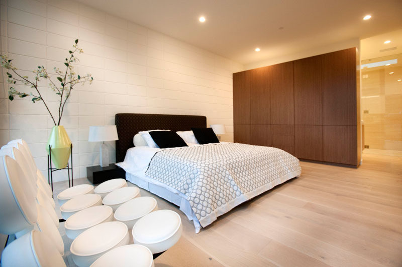 In this bedroom, the dark bed frame and wooden cabinetry contrasts with the white wall and light wood floor.