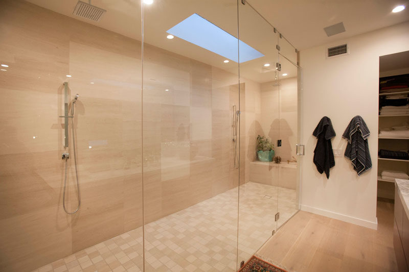 In this bathroom, a large glass enclosed shower stall is home to two separate showers.