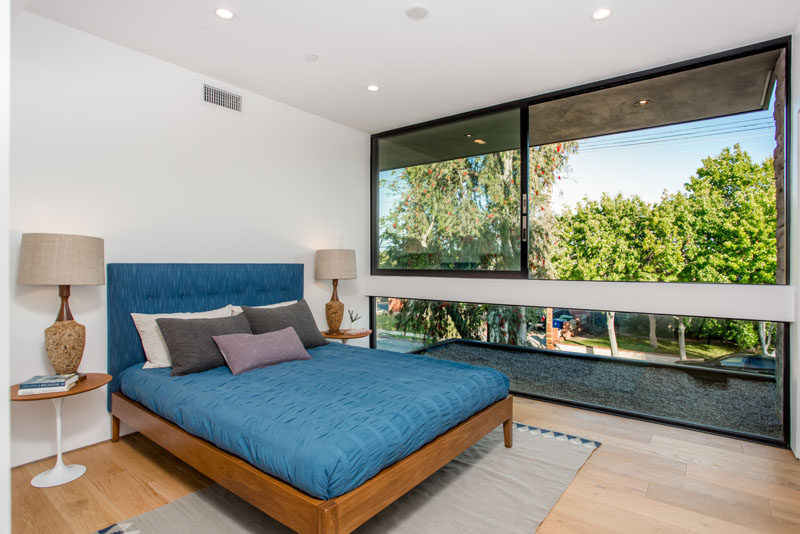 In this bedroom, large windows provide plenty of light and views of the trees and street.