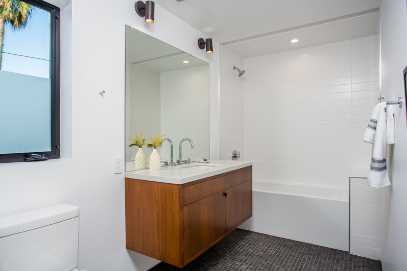 This bathroom features a partially frosted window for privacy, a shower/tub combo with, as well as a floating vanity.