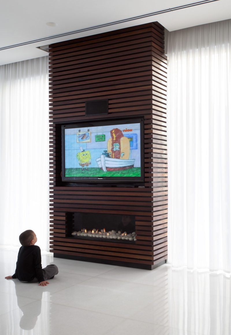 Wrapping an unsightly pillar or inconvenient wall in wood slats and installing a television and fireplace within its design, is a great way to turn otherwise dead space in your home into a functional and unique design detail.