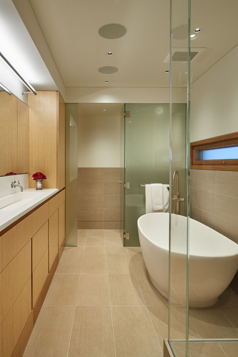 Frosted glass hides the toilet from the rest of this bathroom, and the flooring is made up of limestone tiles.