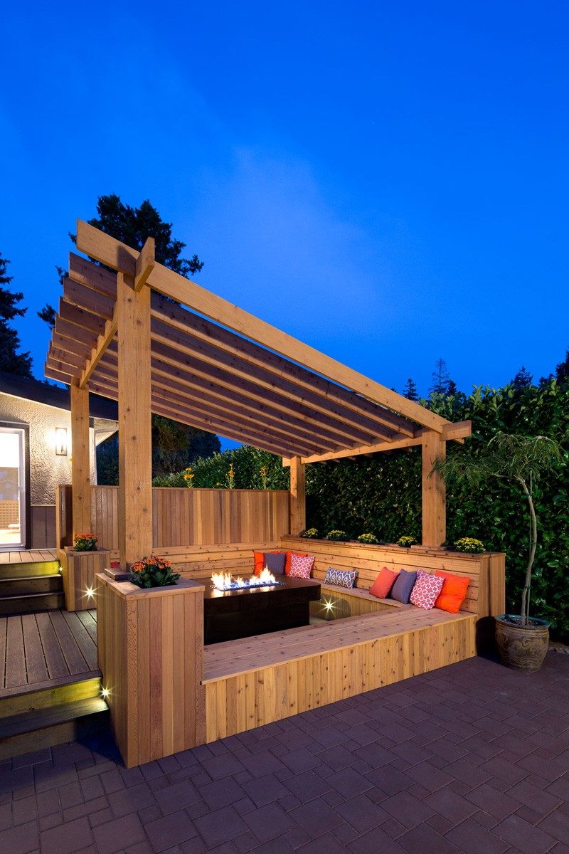 In the backyard of a renovated 1960s home in Vancouver, Canada, is this outdoor space that has built-in bench seating around an outdoor fire.