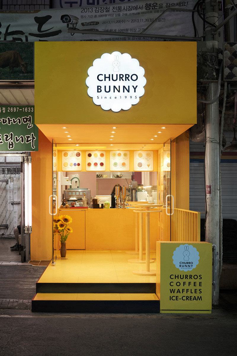 This bright yellow facade highlights a small takeaway café that sells mainly drinks and churros, located in Seoul, South Korea.