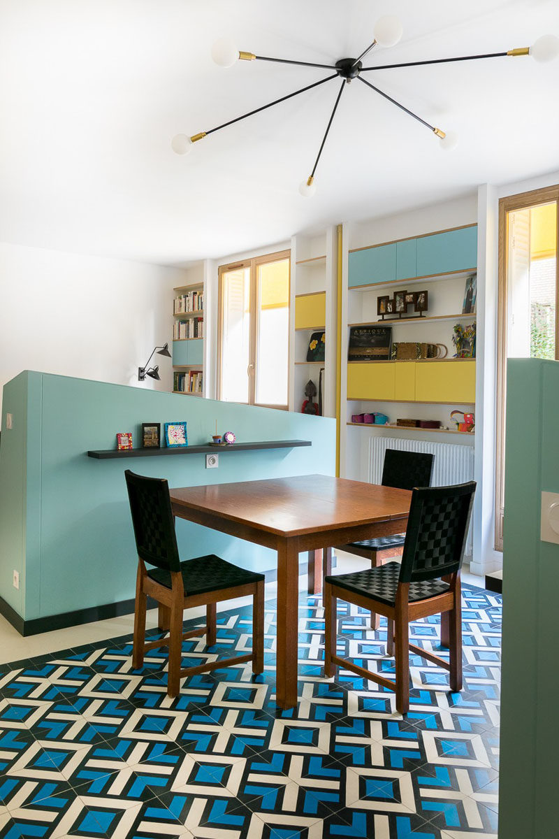 Pony walls separate the dining room from the living room and kitchen. Decorative floor tiles and a sculptural light fixture help to anchor the space.