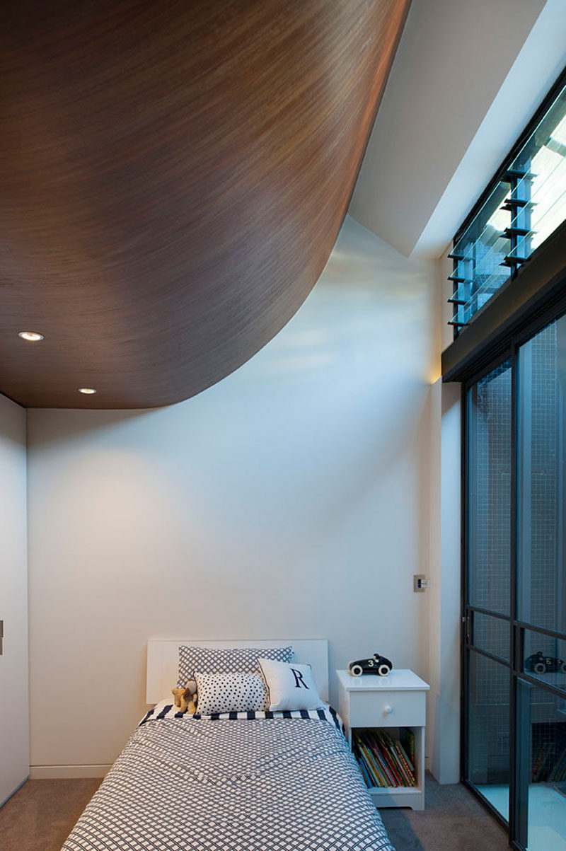 This bedroom has a curved wooden ceiling that contrasts the white walls.