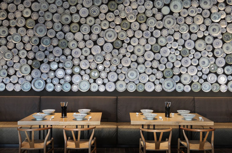 An accent wall in a modern restaurant made from bowls and plates.