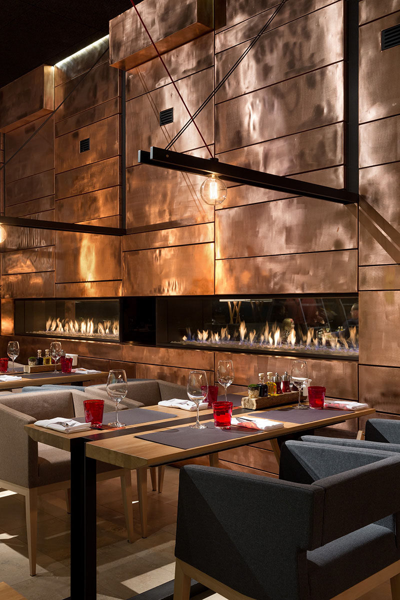 A wall made of copper panels add shine and texture to the interior of this restaurant.