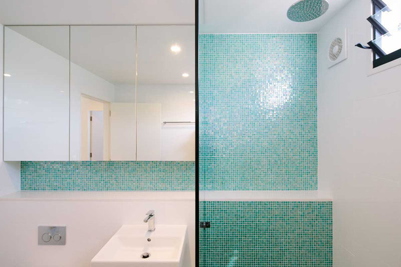 13 Inspirational Examples Of Blue And White Bathrooms // Light aqua tiles line the wall of the shower and the backsplash of this bathroom helping to create a unified, relaxing space.