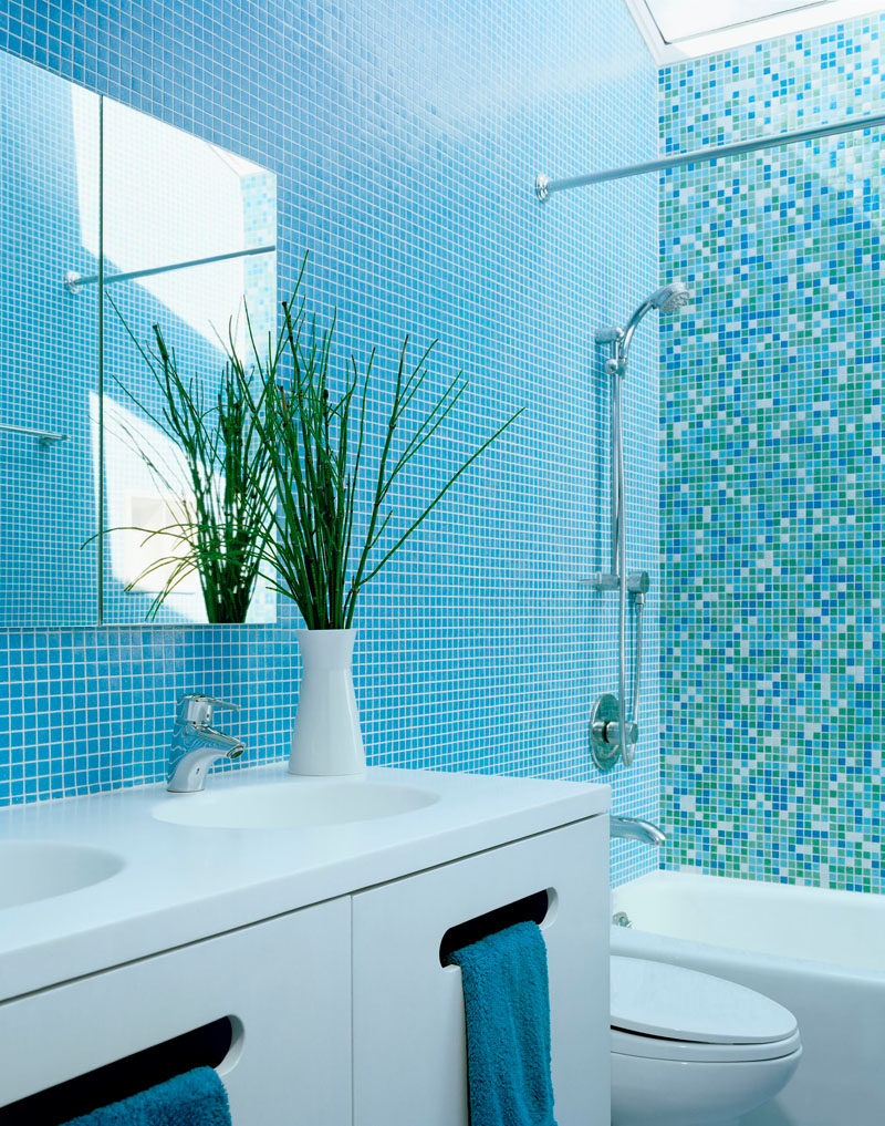 13 Inspirational Examples Of Blue And White Bathrooms // Blue tiled walls broken up by an accent wall of different shades of blue tiles, coupled with the white vanity, make this bathroom fun yet calm.