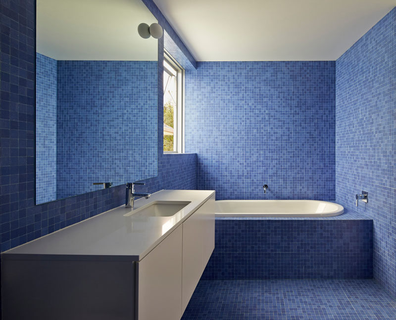 13 Inspirational Examples Of Blue And White Bathrooms // Various shades of blue tiles line the walls and floor of this bathroom, creating a fun atmosphere with a touch of sophistication thanks to the white tub and counter.