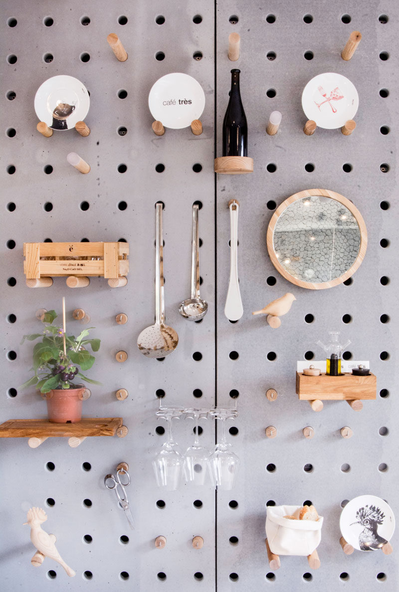 Wall Decor Idea - A gray perforated concrete pegboard lines the wall of this cafe for a unique shelving solution