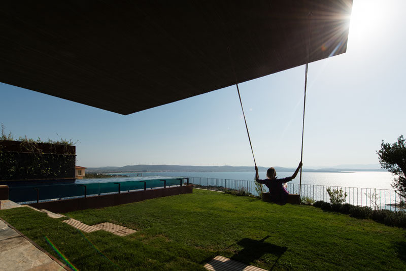 This grassy backyard has a swing and a swimming pool, both positioned to take advantage of the water views.