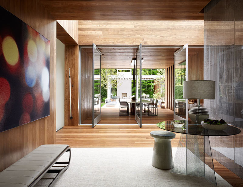 Large glass doors pivot to open the interior of the home to the covered outdoor dining area and backyard.