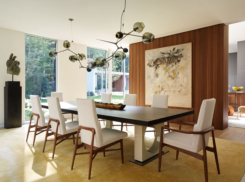 A sculptural light fixture anchors this dining table in the space, and a partial wall separates it from the living room.