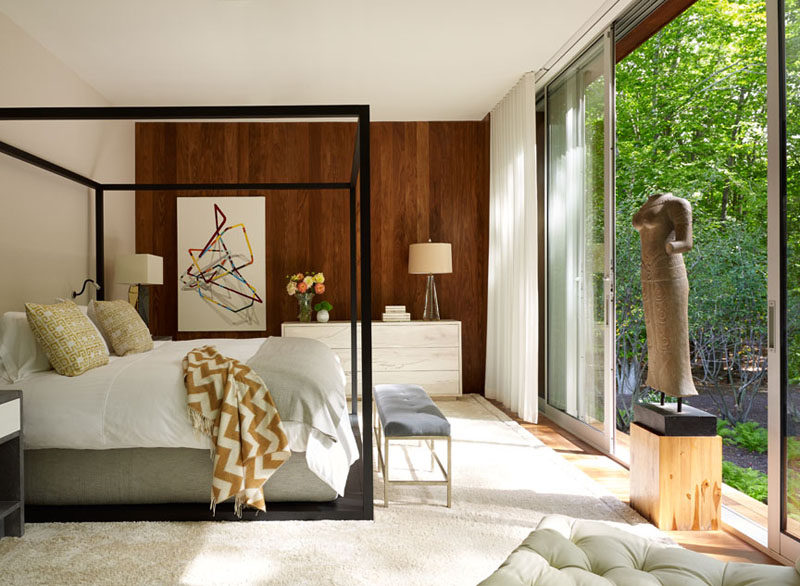 This bedroom has a wooden feature wall and sliding glass doors provide access to the landscaped backyard.