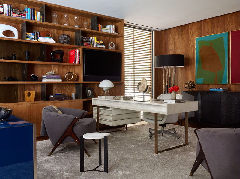 This home office has built-in wooden shelving and enough room for multiple furniture pieces.