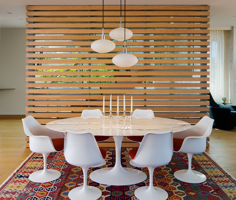 This wooden slat wall partitions off the dining area and gives it a nice backdrop, as well as hiding the stairs behind it.