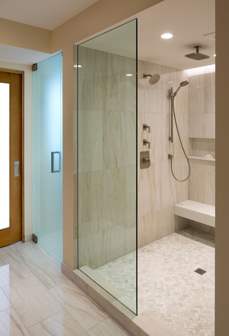 In this shower, there are multiple shower heads to choose from, as well as a built-in bench and shelf.