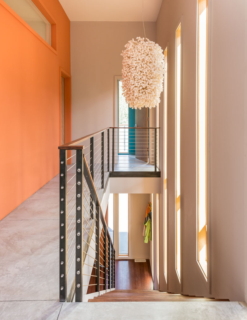 Long windows provide plenty of natural light to this staircase, and the brightly colored walls draw your eye upstairs.