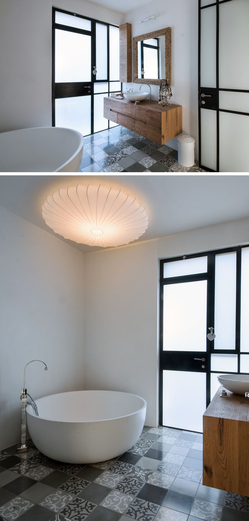 This bathroom has a deep circular tub, a wooden vanity a variety of patterned gray tiles on the floor.