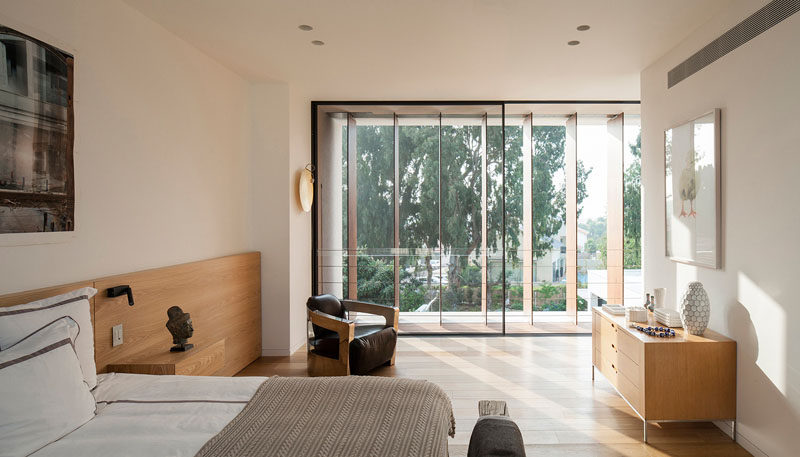 In this master suite, the wooden headboard runs along the wall and has built-in nightstands.