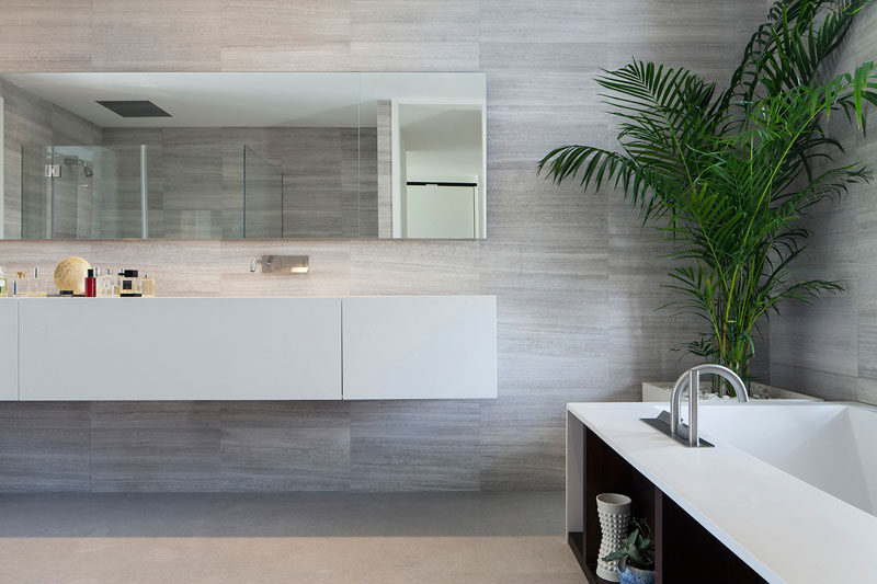 In this master bathroom, the mirror matches the length of the floating vanity. Soft gray tones have been paired with white cabinetry for a contemporary look.