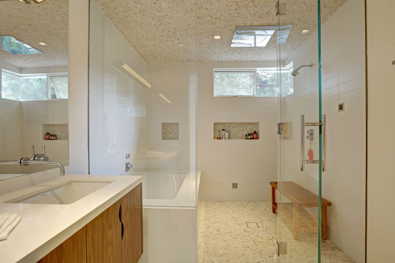 This bathroom has a large glass partition separating the bath and shower from the vanity.