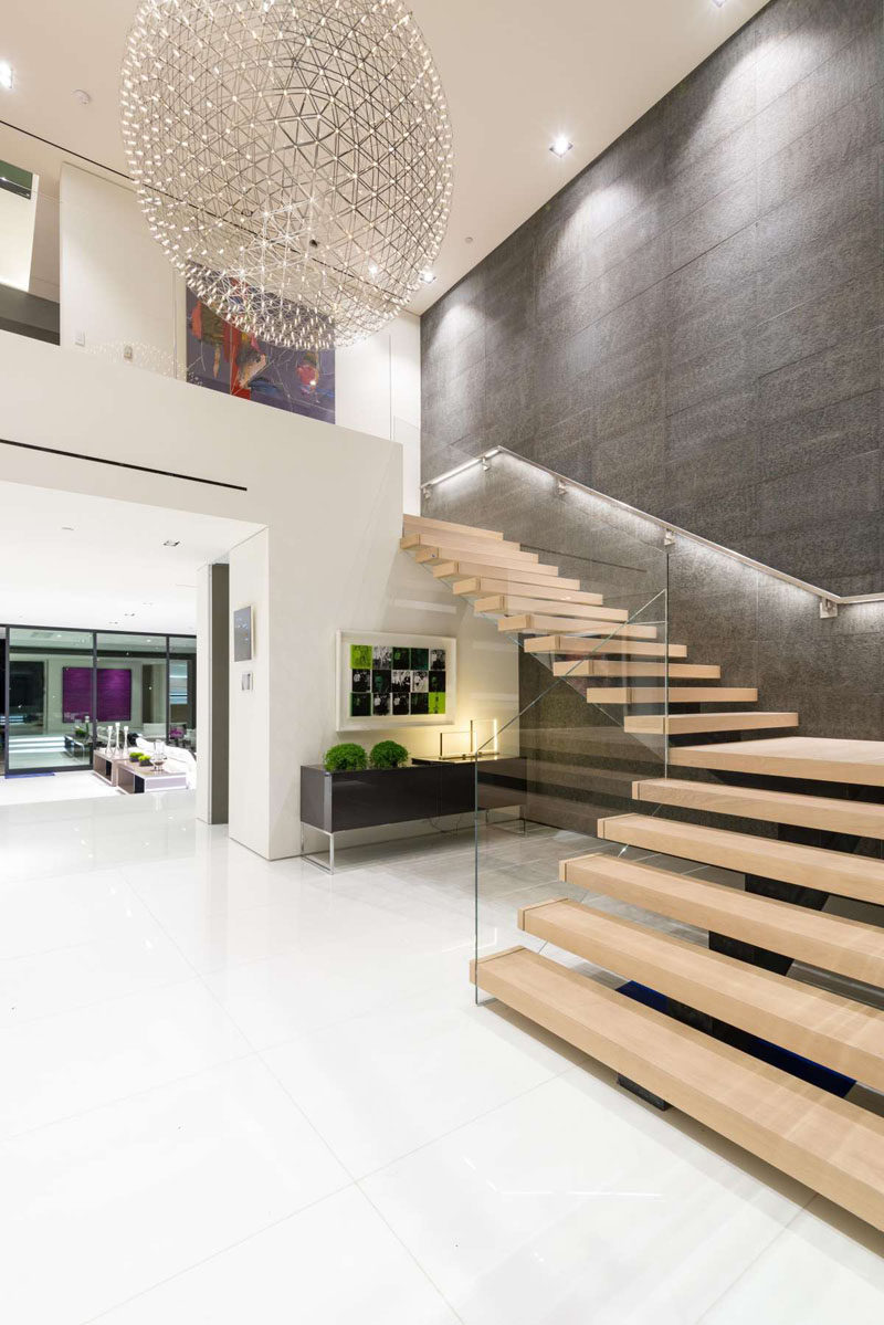 Wood stairs with a glass safety rail lead you upstairs and give you a great view of the 6 ft Moooi chandelier.