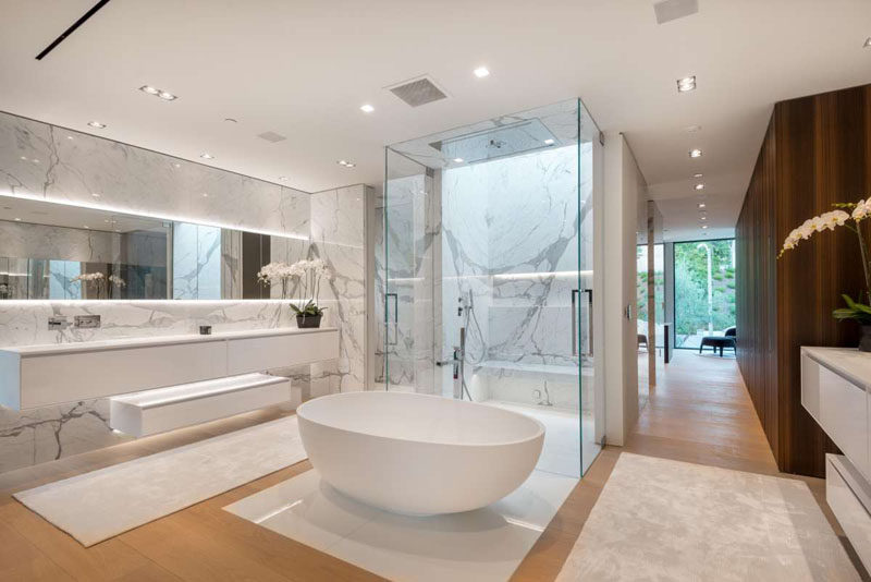 In this master bathroom the designers have used Nano Glass, a scratch & stainproof stone composite slab. The bathroom also has a shower with two doors, a standalone bathtub and a large vanity with backlit mirror.