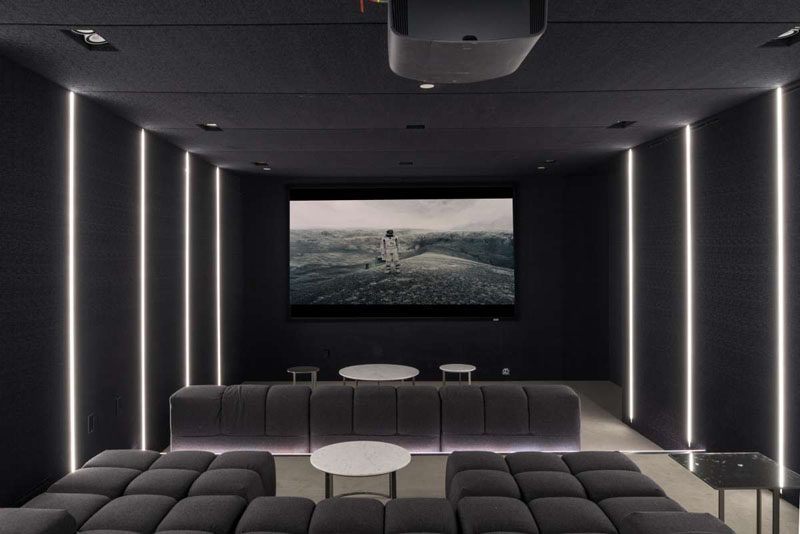 This contemporary home has a dark home theatre room, with comfortable couches and black walls.