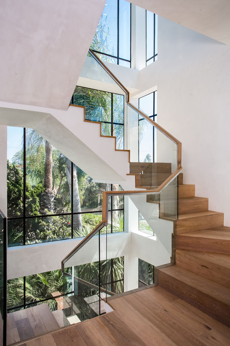 Windows surround these wooden stairs leading you to the upper level of the home.