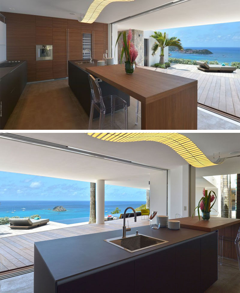 The glass wall in this kitchen can be opened to let in the warm breezes coming off the ocean and makes dinner prep so much more enjoyable. A large island incorporates seating for quick snacks.