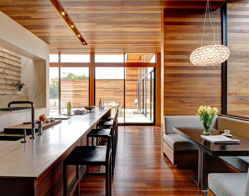 Dining Room Idea - Create A Built-In Dining Nook // This built-in wooden dining nook with gray upholstered cushions, is located just off the kitchen. A pendant light helps to define the dining space, while large windows brighten the shared area. #DiningNook #BuiltInDiningNook #BanquetteSeating #DiningRoom