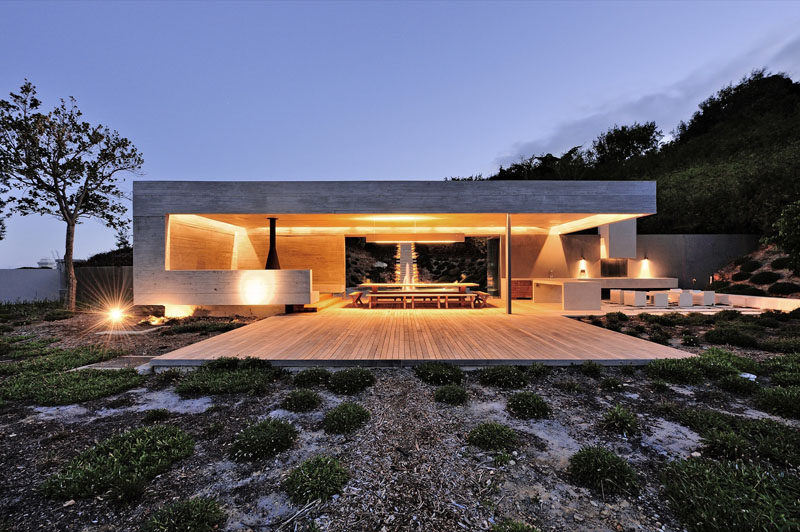 This garden pavilion has an outdoor kitchen, dining area and fireplace with built-in concrete bench seating.