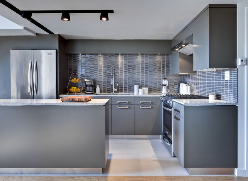 12 Examples Of Sophisticated Gray Kitchen Cabinets // The way the lights are positioned in this kitchen creates shadows on parts of the cabinets but not on others, making the cabinets look like they've been painted different shades of grey.