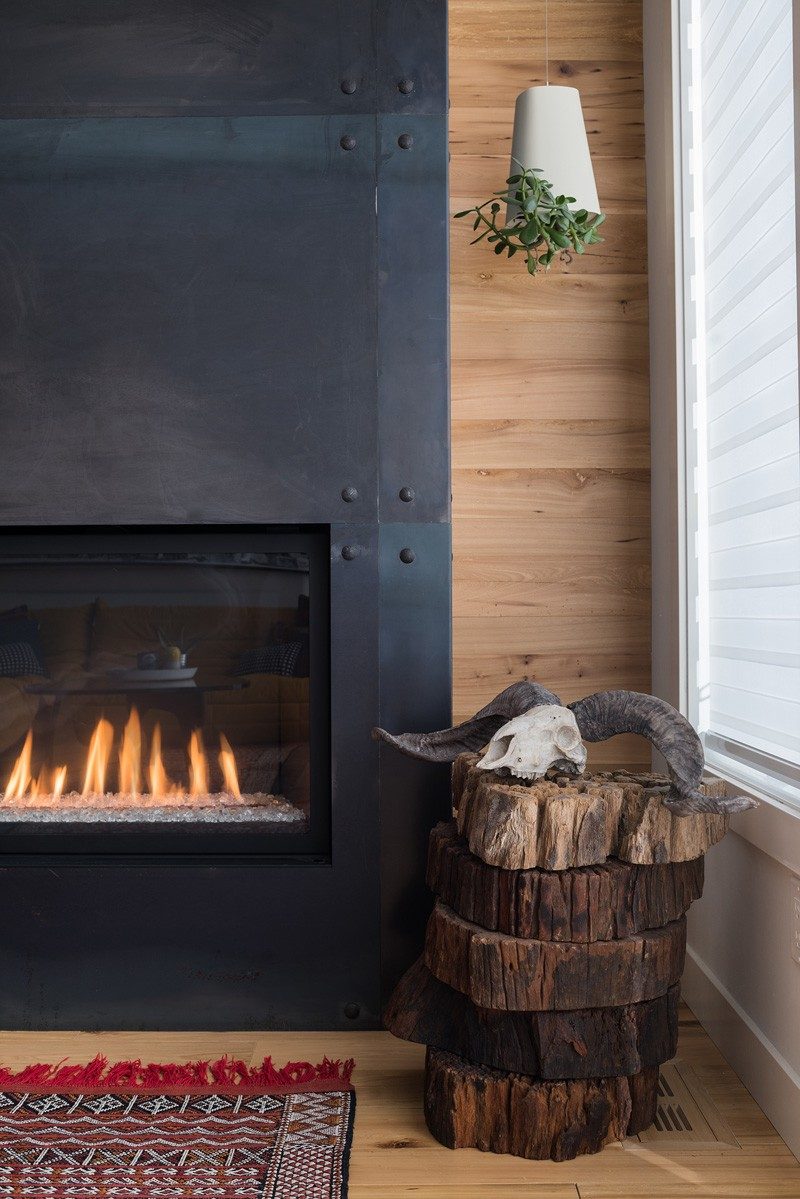 A black fireplace surround has been paired with a wood wall and wood floor in this home.