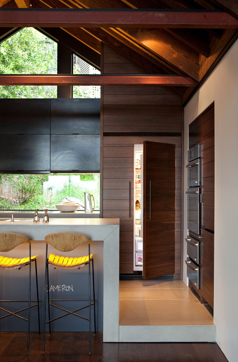 Kitchen Design Idea - 10 Inspirational Examples Of Kitchens With Integrated Fridges // The wood panels covering this fridge, and used as accents throughout the kitchen, hide the fridge and unify the kitchen with the rest of the rustic yet modern home.